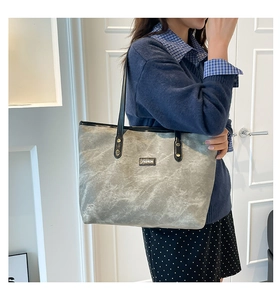 Dettaglio della borsa tote grigia effetto marmo con manici neri e logo moda