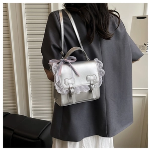 Detail view of silver leather bag with lace trim and black white checkered bow accent