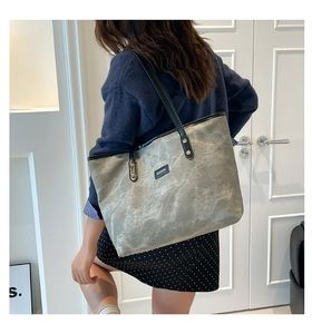 Detailed view of grey washed tote bag with black leather straps and fashion label
