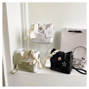 Vue détaillée des mini sacs seaux blanc, vert et noir avec poignées en ruban de soie
