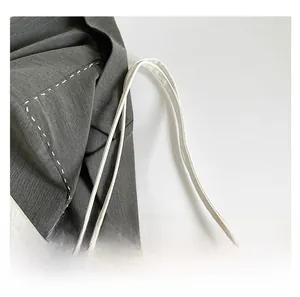 Detail of white leather shoulder bag strap and grey blazer with contrast stitching