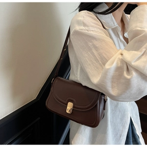Deep brown crossbody bag with gold oval lock shown on model for size reference