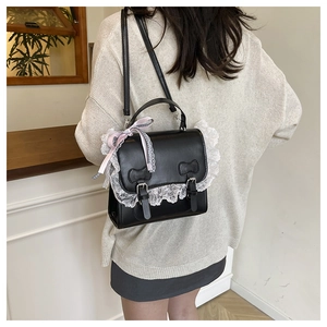 Detail of black leather Lolita bag with white lace trim and pink ribbon bow decoration