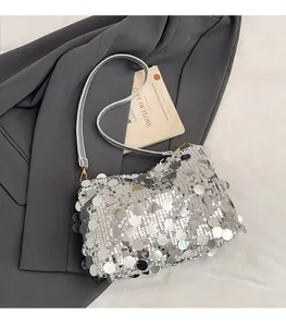 Detail of silver sequined shoulder bag with metallic luster on gray blazer background