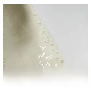 Close-up of beige lychee grain leather with repeated logo pattern detail for bucket bags