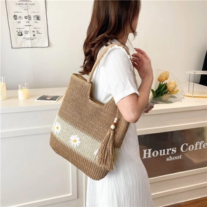 Fashionable straw woven tote bag with daisy embroidery and tassel detail for summer
