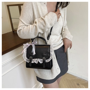 Detail of black PU leather handbag with white lace trim and bow embossing details