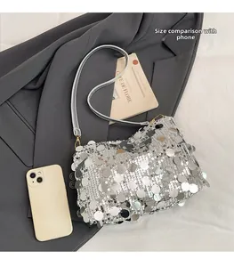 Size comparison of silver sequined shoulder bag next to a mobile phone for scale
