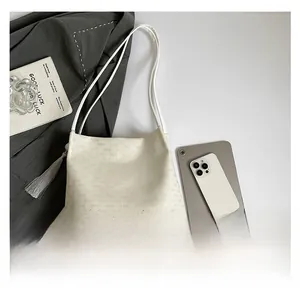 Flat lay of white leather bucket bag with fringe and embossed logo pattern