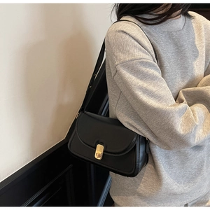 Detail of minimalist black leather crossbody bag with refined golden metal buckle clasp