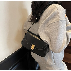 Detail of minimalist black leather crossbody bag with elegant gold metal twist lock