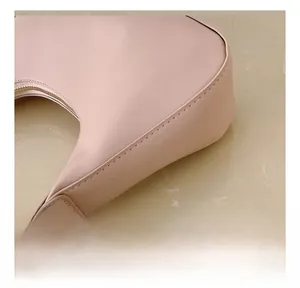 Close-up of the smooth pink faux leather underarm bag showing detailed curved stitching