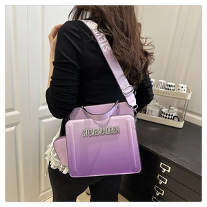 Detail of purple gradient crossbody bag with rhinestone logo and wide strap on model