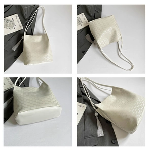 Detail view of beige monogram bucket bag with tassel charm and sleek shoulder strap