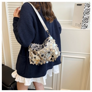 Detail of silver sequin shoulder bag with white leather strap on a model shoulder