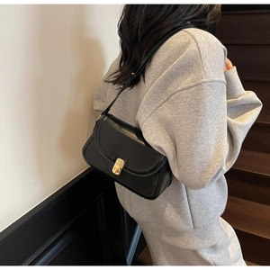 Detail of classic black leather shoulder bag with gold metal twist lock on model