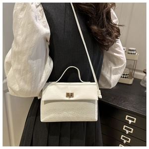 Detail of elegant cream leather handbag with gold twist lock and fine embossed texture