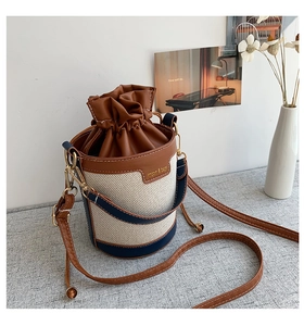 Close-up of contrast color cylinder bucket bag with canvas texture and drawstring closure