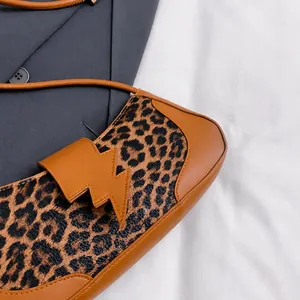 Primer plano de un bolso de hombro con estampado de leopardo y cierre de rayo original.