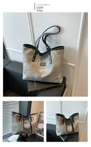 Dettaglio della borsa tote grigio chiaro con manici in pelle nera e rivetti in metallo