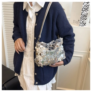Close-up of silver sequin shoulder bag with metallic round scales and slim leather strap