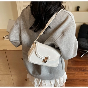 Minimalist white leather crossbody bag with adjustable strap shown on model's back