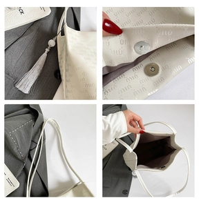 Detail view of cream bucket bag showing magnetic clasp, tassel, and embossed texture