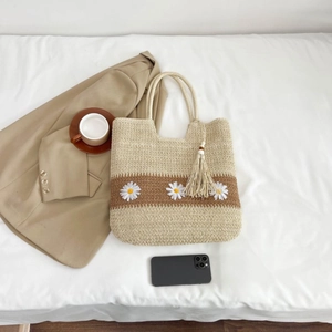 Handwoven straw tote bag with daisy embroidery and fringe detail for summer beach vacations