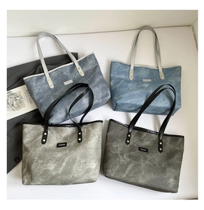 Dettaglio di grandi borse tote in tela marmorizzata con etichetta fashion e rivetti