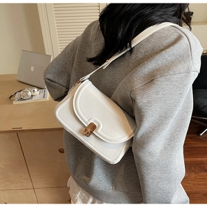 Minimalist white leather crossbody bag with golden rectangular turn-lock and adjustable strap