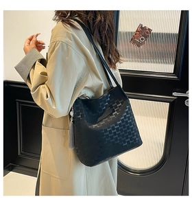Close-up of the black hobo bag with letter prints and a grey tassel charm detail