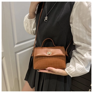 Brown leather satchel with embossed patterns, gold swivel lock and slim shoulder strap