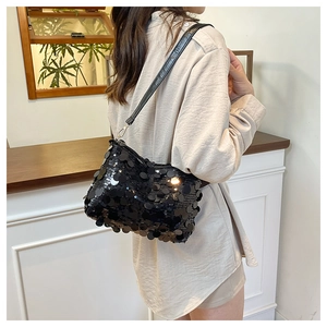 Detail of a chic black sequined shoulder bag with glossy round sequins and leather strap