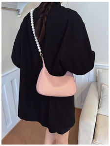 Detail of pink hobo shoulder bag with pearl strap and fashion text on matte leather