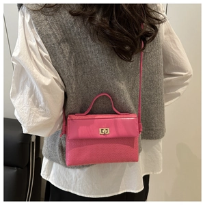 Detail of fuchsia crossbody bag with gold twist lock and elegant textured finish