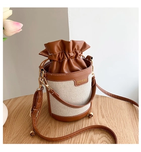 Detail of retro color-block bucket bag with canvas stitching and brown leather drawstring