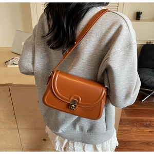Caramel brown leather crossbody bag with vintage metal turn-lock closure on model