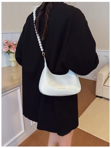 Detailed view of off-white hobo bag with elegant pearl strap and gold foil lettering