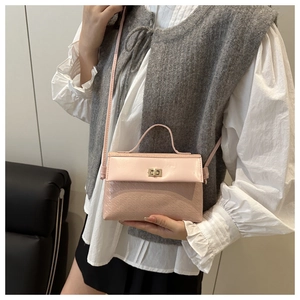 Close-up of light pink textured square handbag with golden rotating lock and cross-body strap