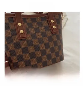 Detail showing brown checkered pattern with gold metal rivets and leather handle