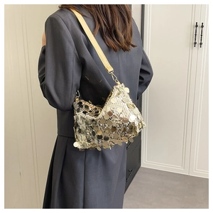 Detail of shimmering gold sequin shoulder bag with leather strap on grey blazer