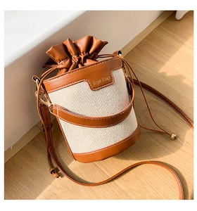 Detail of a vintage-style bucket bag with woven fabric texture and dark brown drawstring