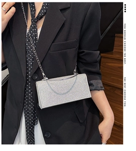 Detailed view of silver rhinestone clutch with metal chain on elegant model