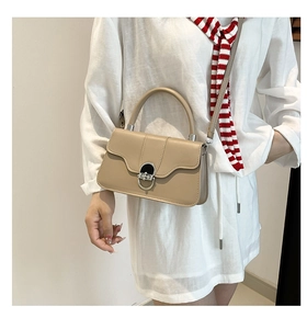 Close-up of matte beige leather shoulder bag with silver metal buckle and curved handle