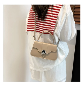Detail of a khaki leather crossbody bag featuring a silver metal buckle and top handle