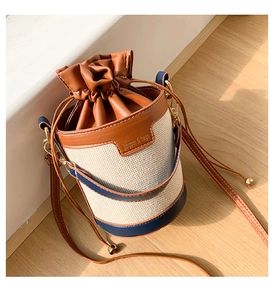 Detail of drawstring bucket bag with contrast leather trim and golden metal hardware