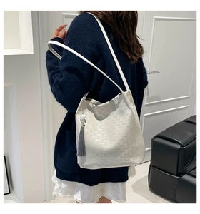 Detail of off-white tote bag with letter texture and grey tassel on shoulder strap