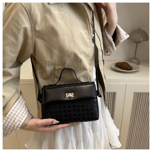 Detail of elegant black crossbody bag with houndstooth texture and golden twist lock closure