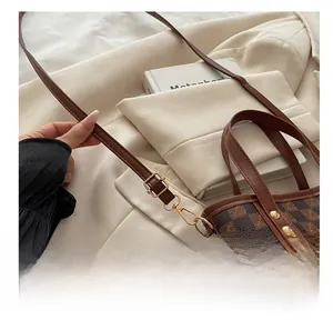 Detail of checkered bucket bag featuring golden metal hooks and adjustable strap