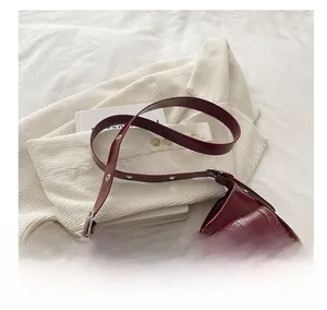 Dettaglio della borsa sottobraccio rosso scuro con due tasche frontali e fibbie in metallo